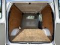 Interior view of a 2013 Ford Econoline van showing a spacious empty cargo area with wooden flooring and wooden side panels, featuring a metal partition at the front