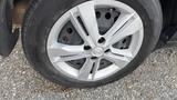A close-up view of a silver alloy wheel from a 2019 Nissan Kicks featuring a five-spoke design and a black tire with visible tread pattern