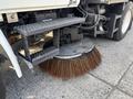 A 2012 International DuraStar 4300 street sweeper with a large rotating brush attachment for cleaning roads