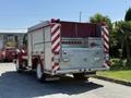 A red and silver 1991 International 4600 fire truck with reflective stripes and multiple compartments on the rear for equipment storage