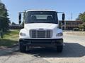 A white 2014 Freightliner M2 106 truck facing forward with a large front grille and side mirrors extended
