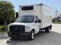 A 2023 Ford E-450 truck with a white cargo box and an air conditioning unit on top parked on a concrete surface