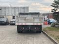 A 2014 Ford F-550 flatbed truck viewed from the rear with a silver dump body and black tarp covering the bed