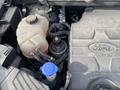 A 2017 Ford Edge engine compartment showing the coolant reservoir and various engine components with the Ford logo on a black engine cover
