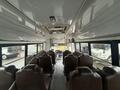 Interior of a 2021 Ford Econoline bus featuring brown seating and an overhead storage compartment