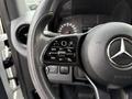 Close-up of a steering wheel with controls for cruise settings and the Mercedes-Benz logo in the center