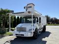 A white 2010 Freightliner M2 106 utility truck with an elevated work platform and side compartments for tools and equipment