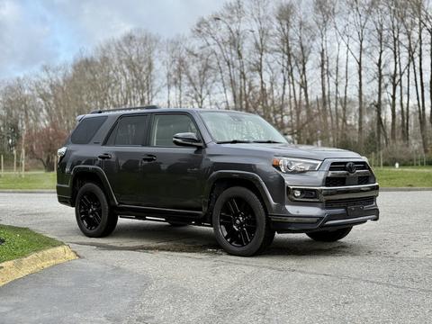 A 2021 Toyota 4Runner in a dark color with black alloy wheels parked on a gravel surface