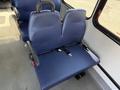 A blue fabric seat with armrests and a seatbelt in a vehicle interior