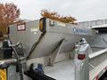 A stainless steel salt spreader attached to a truck bed with labels for Western and Ice Breaker on its side