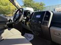 Interior of a 2018 Ford F-150 featuring a steering wheel a central console with controls and a gear shifter with cloth seats and a floor mat visible
