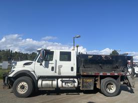 A white 2014 International 7400 truck with a black dump bed equipped for hauling and transporting materials