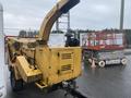 A yellow 2010 Vermeer Corporation BC1000XL wood chipper with a large chute and engine exposed in the foreground