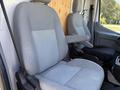 Two gray front seats of a 2015 Ford Transit with one seat having an armrest and the other seat appears to be adjustable