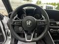 Steering wheel of a 2023 Alfa Romeo Giulia featuring a black leather finish and integrated controls for audio and driving settings