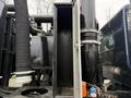 A 2018 Kenworth T800 with an open storage compartment revealing an empty interior and various connected hoses and pipes in the foreground