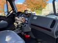 Interior view of a 2011 Freightliner M2 106 showcasing the dashboard with controls gauges and a mounted GPS device along with a fire extinguisher near the driver's seat
