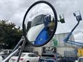 A white and blue 2013 International DuraStar 4300 truck is reflected in the side mirror showing its front and driver's side visible