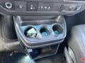 A black cup holder console with three circular openings and a small compartment for storage in a 2023 GMC Savana vehicle