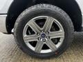 A close-up of a silver alloy wheel on a 2014 Ford F-150 featuring a distinctive five-spoke design and all-terrain tire