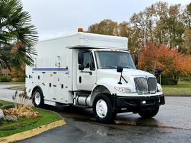 A 2011 International 4400 truck with a white exterior featuring a boxy cargo area and various compartments on the sides