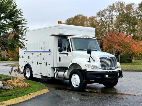 A 2011 International 4400 truck with a white exterior featuring a boxy cargo area and various compartments on the sides