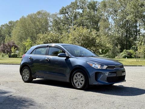 A blue 2018 Kia Rio5 hatchback parked with a sleek design featuring a compact body and distinct front grille