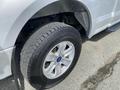 A silver 2015 Ford F-150 with a focus on its wheel and tire showing the tread design and alloy rim