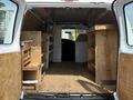 Interior of a 2008 Ford Econoline van with wooden shelving on both sides and a wooden floor showing the spacious cargo area