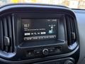 Dashboard of a 2018 GMC Canyon showing a touchscreen display with a radio station tune and song title on the screen at 320 AM