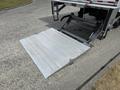 A metal loading ramp extended from the back of a 2022 International MV607 truck designed for cargo loading and unloading