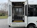 A 2013 Chevrolet Express with an open rear door revealing a wheelchair lift in a lowered position with safety barriers and yellow platform steps