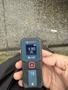 A person's hand holding a Bosch laser distance measurer displaying a measurement of 9.305 feet