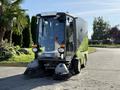 A 2015 Tennant 636 Green Machine compact street sweeper featuring two front brushes a driver cabin and a green and black design