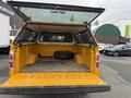 A yellow 2014 Ford F-150 pickup truck with an open bed revealing a tire and a clean interior space
