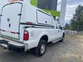 A 2014 Ford F-350 SD truck with a white service body and a closed cargo area in the back featuring a 4x4 decal on the side