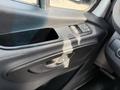 The interior door panel of a 2023 Mercedes-Benz Sprinter featuring window controls and a door handle