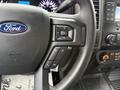 Close-up of the steering wheel of a 2022 Ford F-550 featuring controls for volume and functionality with the Ford logo prominently displayed