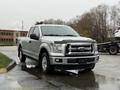 A 2015 Ford F-150 pickup truck with a silver exterior parked on a wet surface