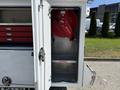 The image shows the open compartment of a service truck featuring a hose reel mounted on the wall and red tool drawers above it