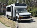 A 2020 Chevrolet Express shuttle bus with a white exterior and black accents parked at an angle, featuring large windows and a prominent front grille