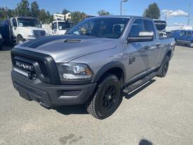 A 2021 RAM 1500 pickup truck in gray with a black grille and oversized wheels showcasing a rugged design and aggressive stance