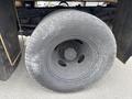 A close-up of a black tire from a 2004 Ford F-350 SD showing a worn tread and a central wheel hub with multiple bolt holes