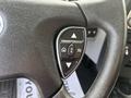 Close-up of a steering wheel control panel featuring navigation and multi-function buttons including arrows and an "OK" button