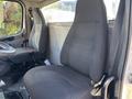 Interior view of a 2005 Freightliner M2 106 showing two gray cloth seats one with a seatbelt the driver seat is positioned with a steering wheel visible