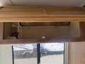 Interior view of a 1976 GMC Motorhome with a wooden overhead storage compartment and white paneling