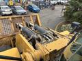 A 2012 Caterpillar 980 showcasing hydraulic cylinders and a bucket attachment with yellow and gray coloring