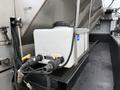 A white liquid tank with fittings and hoses attached on a vehicle's flatbed