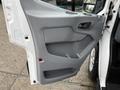 A close-up view of the driver side door panel of a 2019 Ford Transit featuring a gray plastic design with a door handle and storage compartment