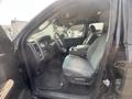 Interior view of a 2015 RAM 1500 showing a driver's seat, steering wheel, and center console with gray cloth upholstery and floor mat
